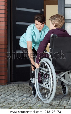 Female caregiver helping disabled woman on wheelchair entering home