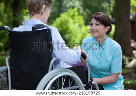 Young beautiful nurse spending sunny day with disabled woman at park