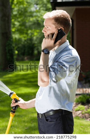 Businessman watering grass in a garden, vertical