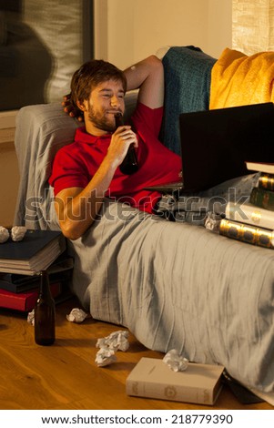Young attractive student drinking beer on his couch