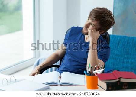 Lazy student looking through the window in his study room