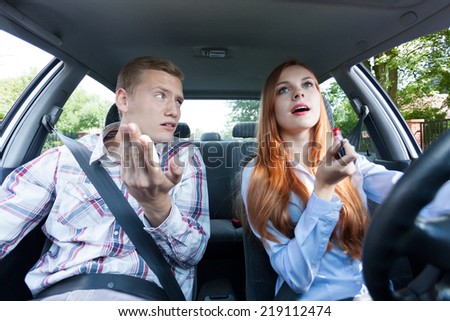 Frivolous woman making up in a car