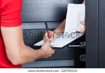 Woman signing parcel shipment documents on clipboard