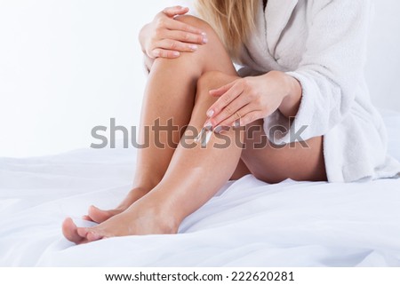 Woman in dressing gown using body cream