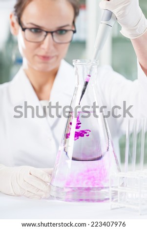 Chemist putting purple liquid into the flask