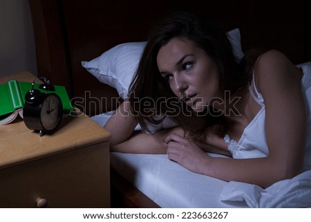Woman in bed looking at clock at night
