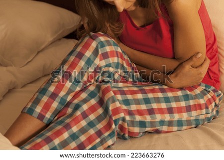 Young woman in bed suffering from abdominal pain