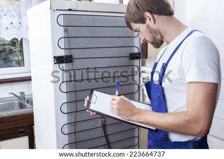 Horizontal view of handyman during fridge repair