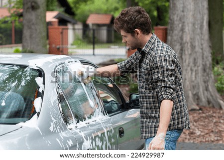 Young tall man washing his silver car