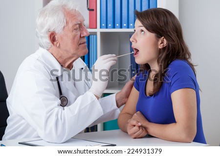 General practitioner examining throat of young woman