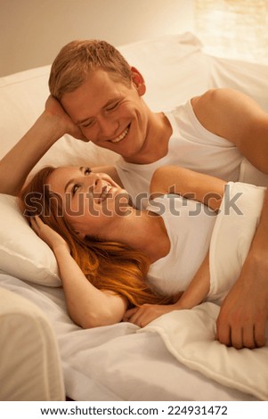 Smiling happy married couple lying in bed