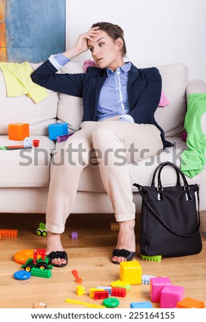 Tired young mother sitting on sofa after hard day at work
