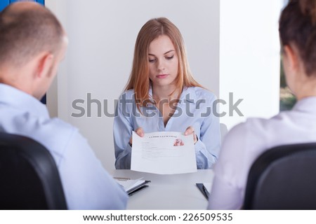 Young stressed female applicant giving her curriculum vitae