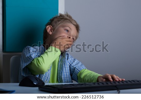 Horizontal view of yawning kid using computer