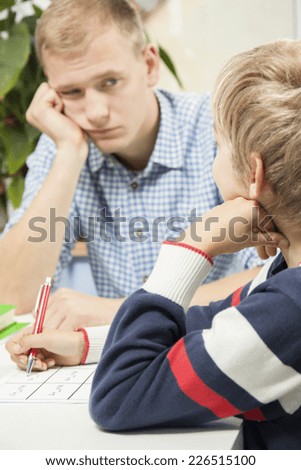 Bored father helping son with homework, vertical