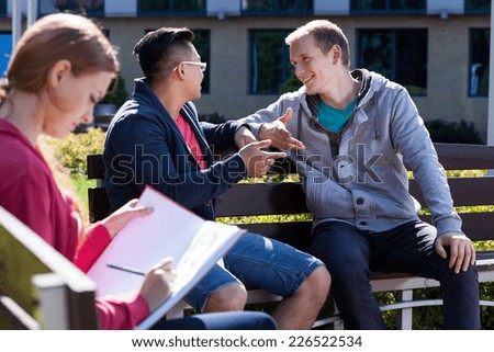 University friends sitting on the bench and talking
