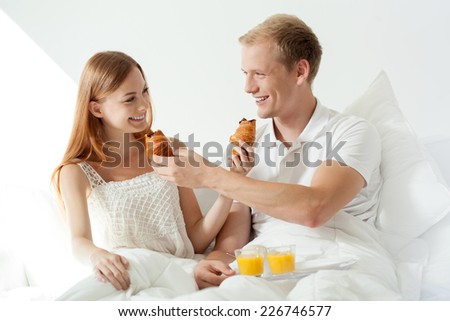 Young happy couple feeding each other for breakfast