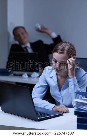 Young worker bullying his young attractive work colleague