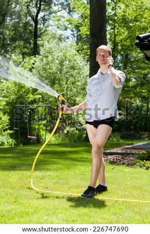 Man without trousers watering the plants in garden