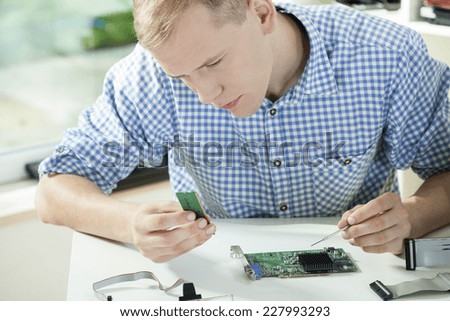 Man wearing check shirt repairing his computer