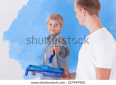 View of boy painting wall with father
