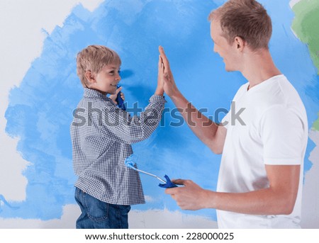 Young father giving high five to his little son during working together