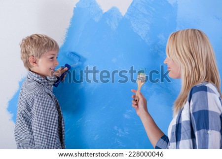 Mother and son having fun from painting the wall, horizontal