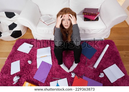 A frightened girl stuck in a room with schoolwork all around