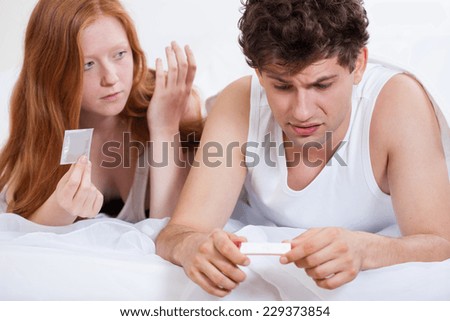 Scared young man holding positive pregnancy test