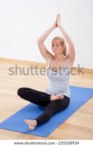 Woman practicing yoga on gym floor mat