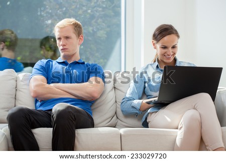 A man bored with his wife surfing on a laptop