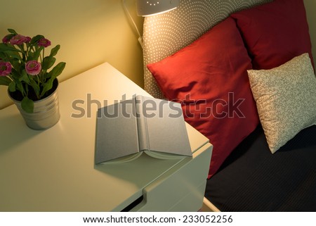 Cozy bedroom interior with book lying on bedside table
