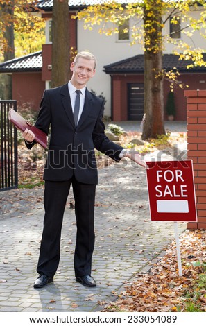 Smiling real estate broker standing in front of new home