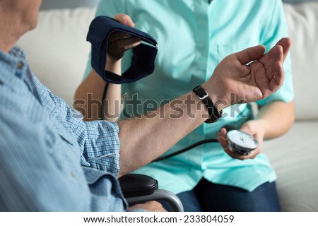 Nurse measuring blood pressure of handicapped man