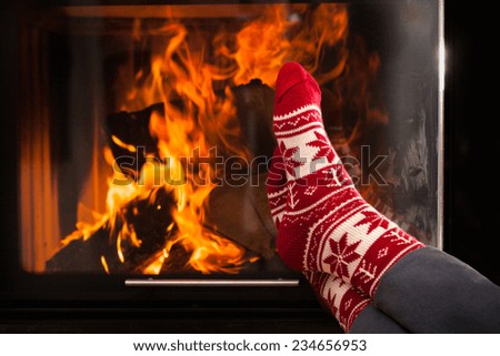Woman heating frozen feet by warm fireplace