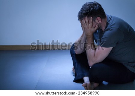 Portrait of lonely depressed man sitting on the floor