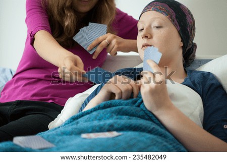 Mom and her sick daughter playing cards in hospital bed