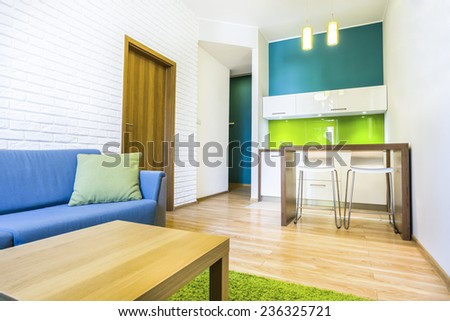 Green hotel room with sofa and kitchenette