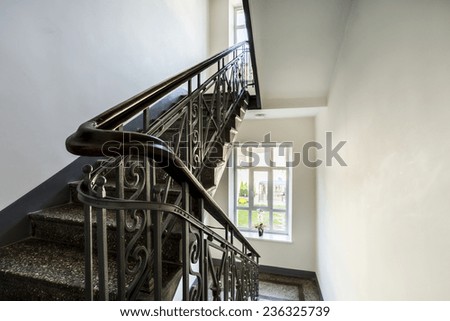 Staircase with old, decorative railing and white walls
