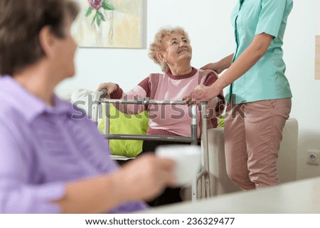 Young helpful nurse and older woman with walker