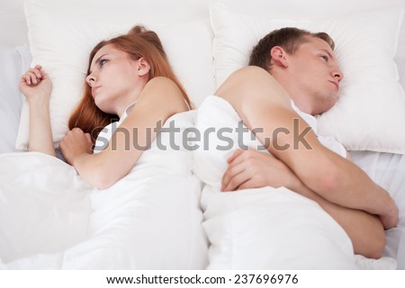 Young offended couple lying in bed after fight