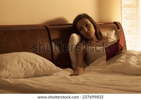Woman reading book in bed and waiting for boyfriend