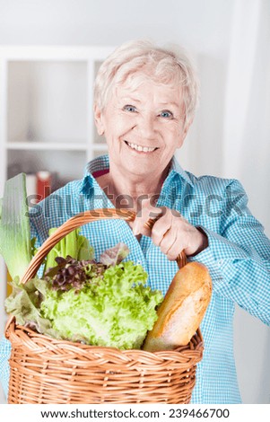 Smiling older woman with basket full of shopping