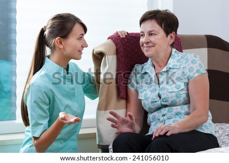 Young beautiful nurse talking with her older patient
