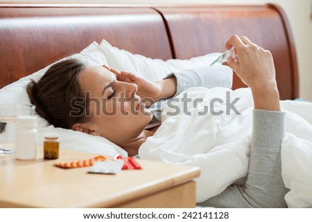 Image of having high fever woman holding thermometer