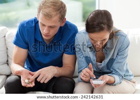 Poor couple sitting on the couch and counting money