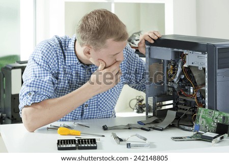 Young concentrated computer specialist thinking of computer repair