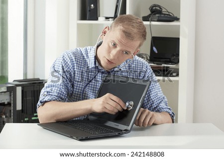 Young handsome computer science auscultating the computer by stethoscope