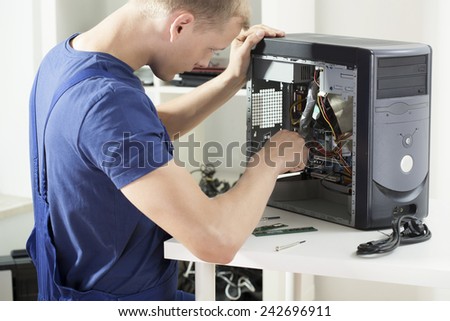 Young smart computer specialist working on broken dismalted computer