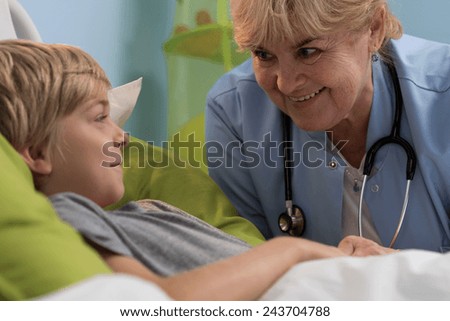 Little sick boy in bed and his elderly female pediatricians